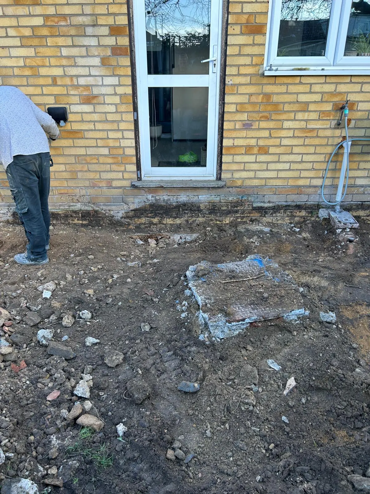 Groundworker starting excavation for an extension beside the rear door of a house